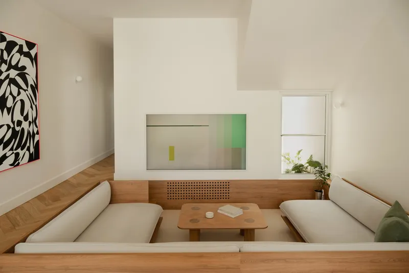 Sunken living room with timber chevron flooring and white fireplace block beneath a double-height ceiling
