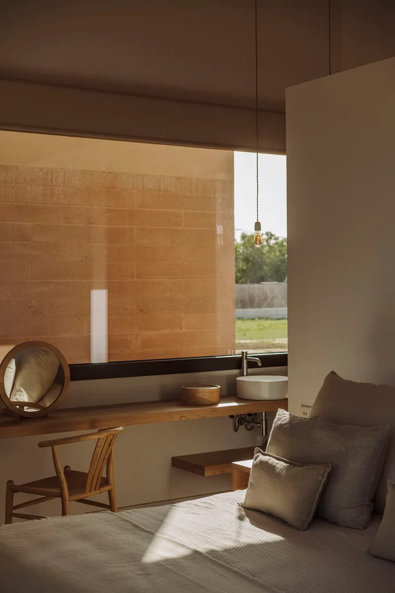 Living area with horizontal clerestory window framing rammed earth wall and pendant light fixture