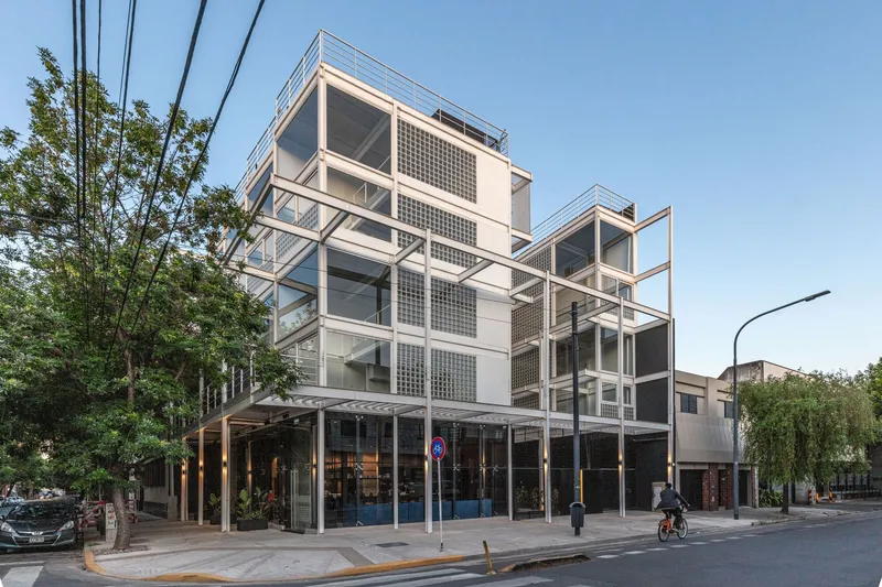 Street view of the white steel frame facade with glass block panels and cantilevered balconies at dusk