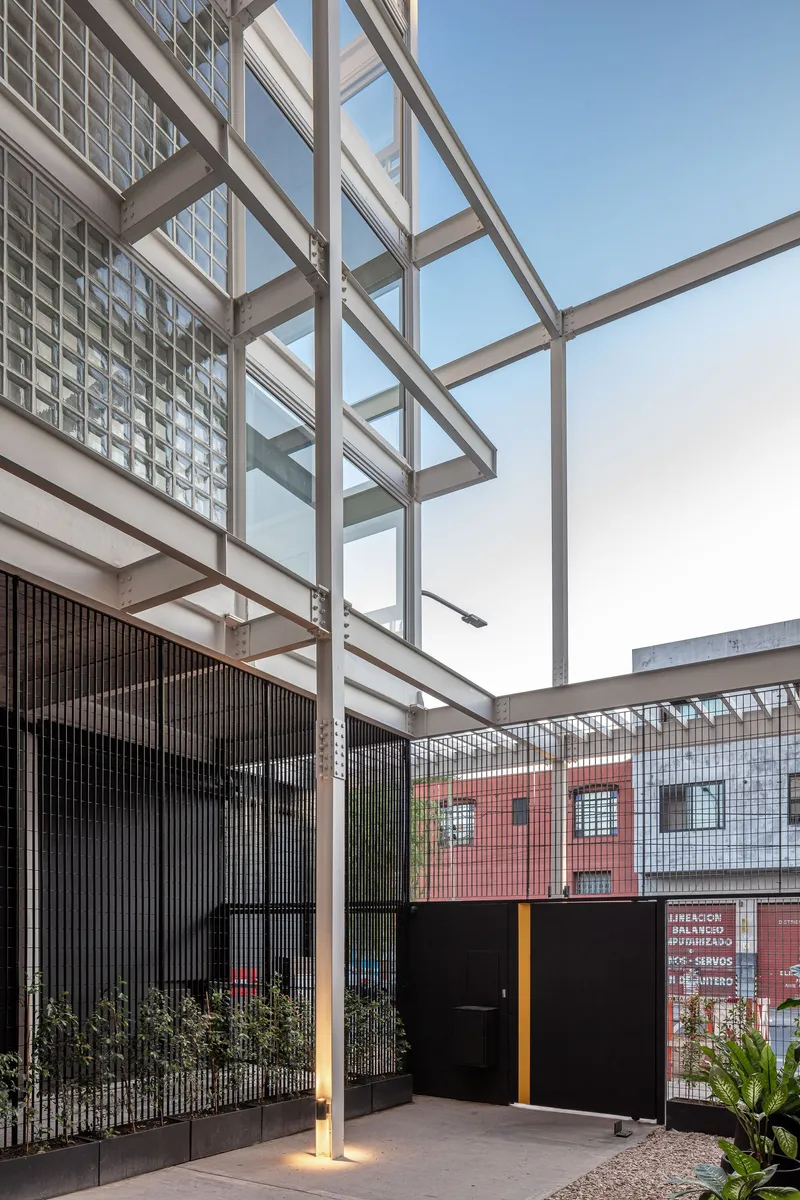 Steel pergola columns framing the entrance with vertical screening and glass block wall in afternoon light