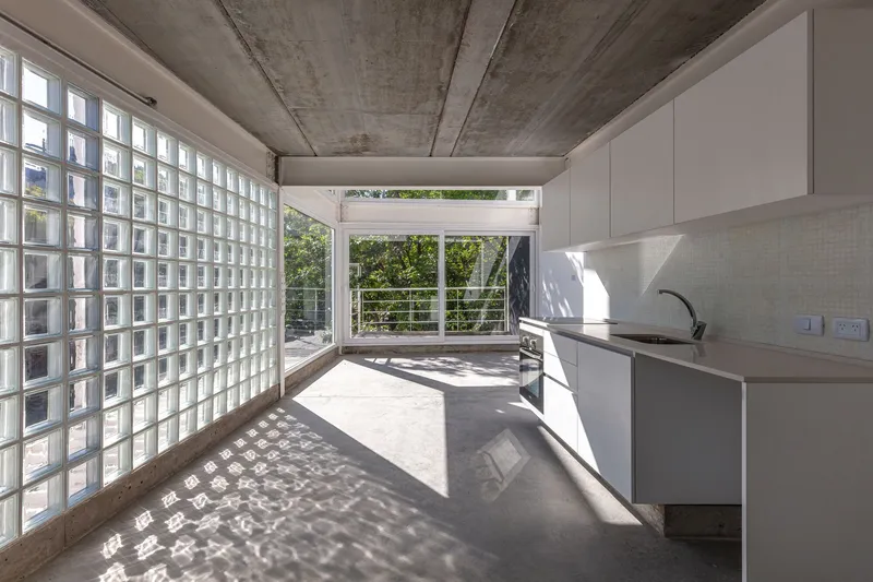 Interior kitchen with glass block wall casting dappled shadows on polished concrete floor