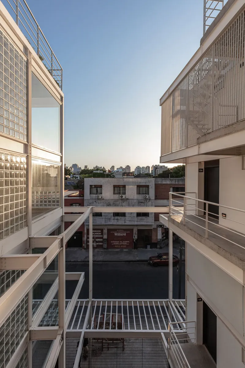 View into a courtyard framed by glass block facades and metal railings at dusk