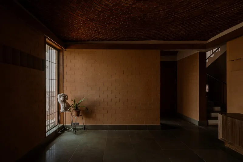 Entry hall with basket-weave brick vaulted ceiling and woven block walls in soft afternoon light