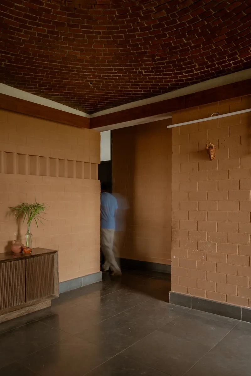 Corner view of doorway with figure passing through beneath a radiating brick vault ceiling