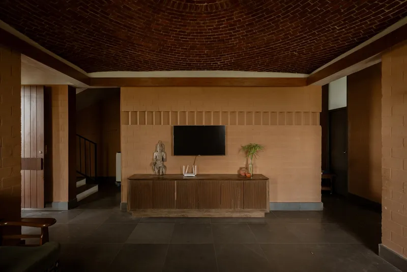 Open room featuring a ribbed timber credenza against a tiled wall beneath a radial brick ceiling