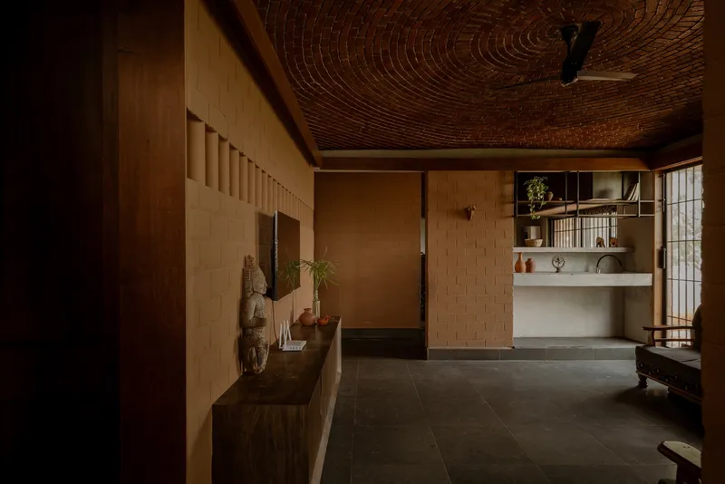 Interior view across dark floor tiles toward built-in shelving and translucent grid screens in warm afternoon light