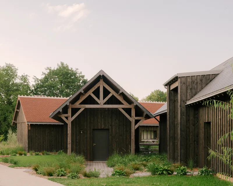 Dark timber barn with exposed gable frame and planted beds in overcast afternoon light