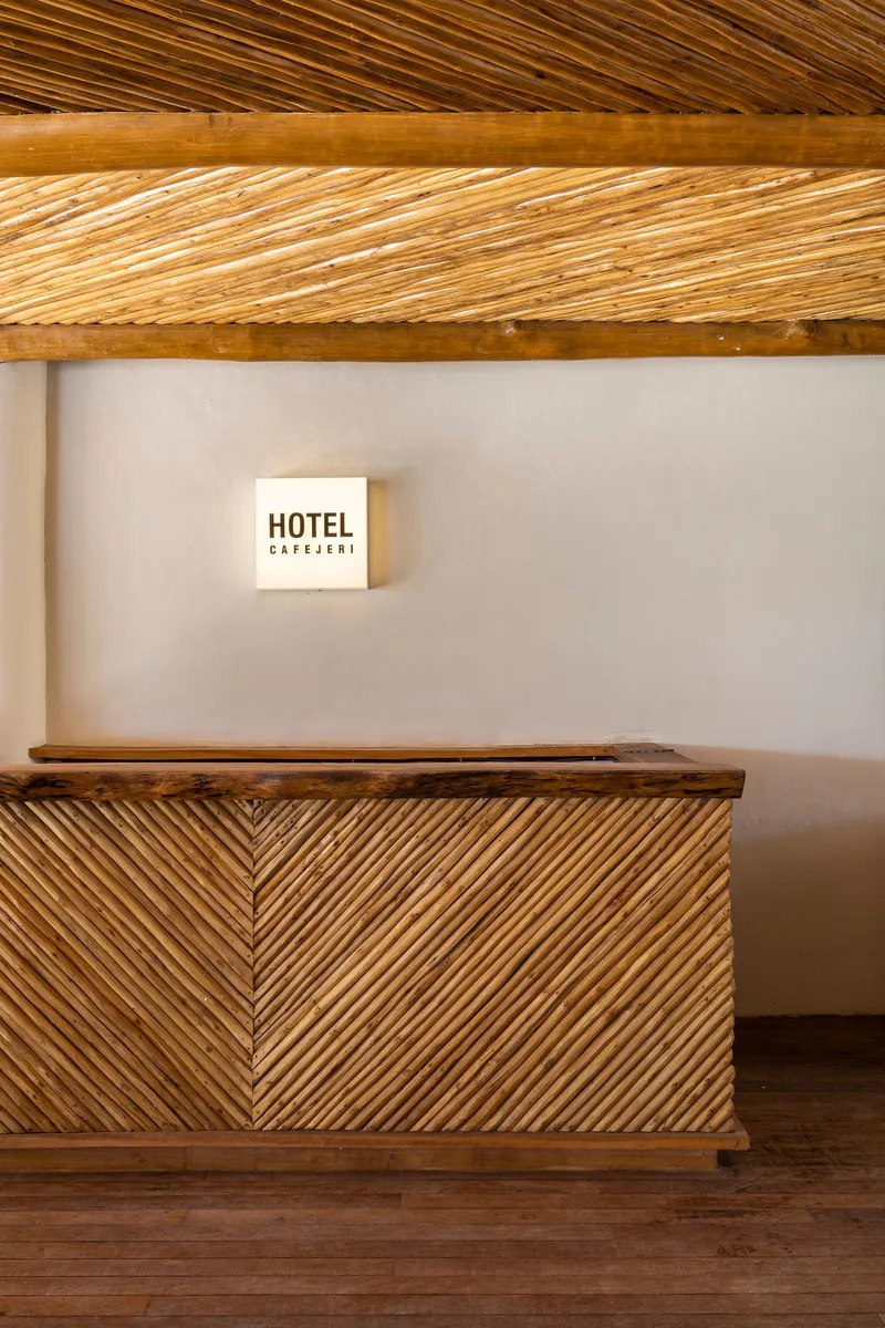Reception desk with herringbone bamboo panels beneath diagonal slatted timber ceiling and wall-mounted signage