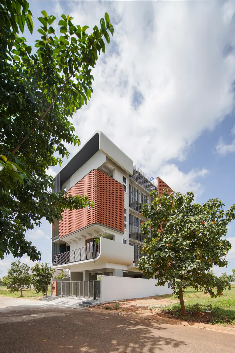 Front elevation revealing stacked terraces and patterned brick volumes under a cloudy sky