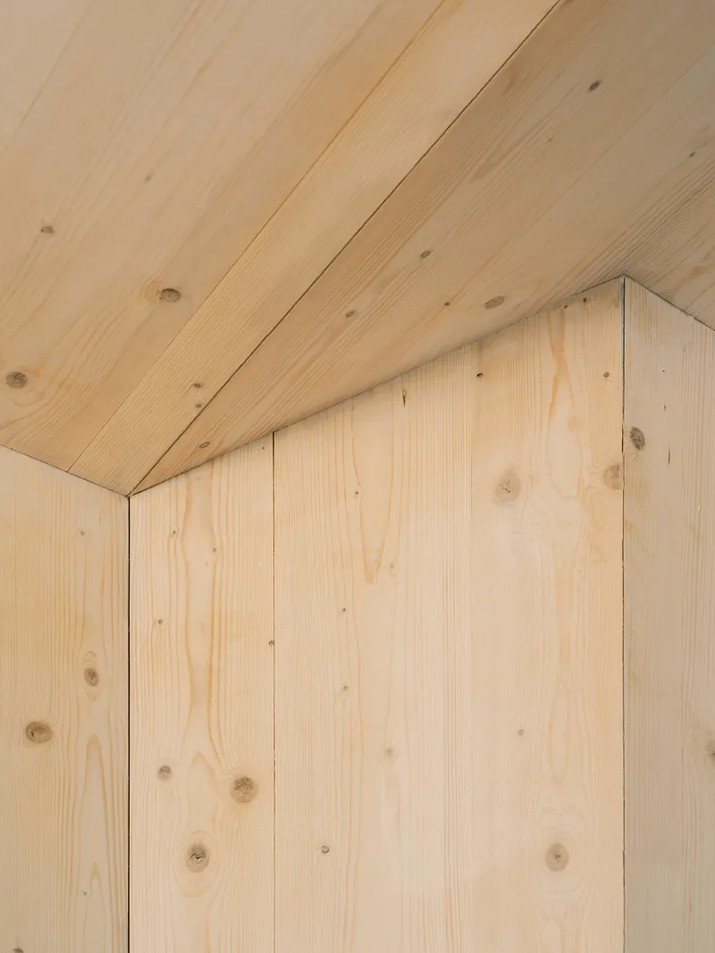 Detail of pale wood planks meeting at an internal corner with visible knots and grain