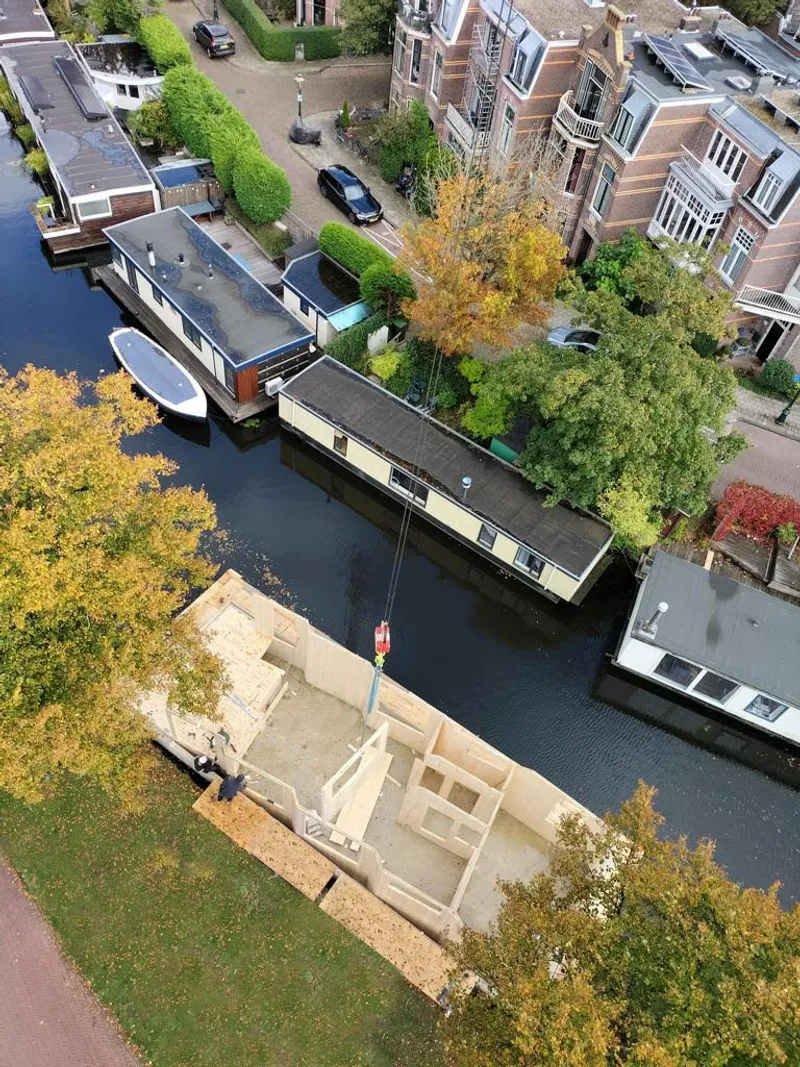 Aerial view of houseboat moored alongside canal with neighboring houseboats and autumn trees