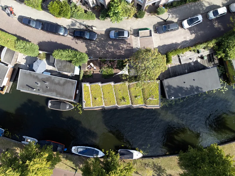 Aerial view of the green roof with planted strips floating among parked cars and neighboring houseboats
