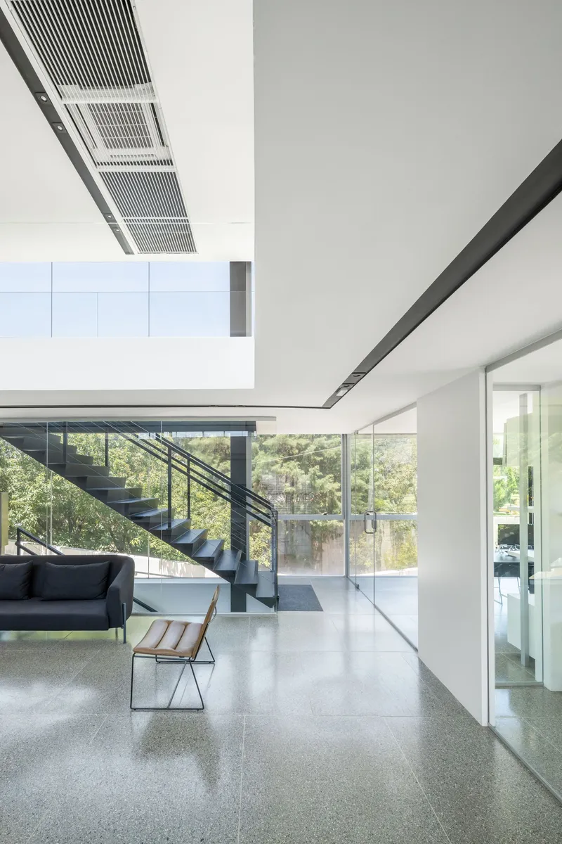 Open living space with polished terrazzo floor and steel stair beneath linear ceiling vents
