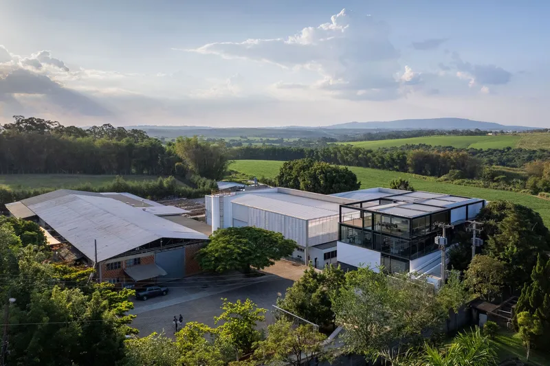 Aerial view of the industrial complex with metal roofs surrounded by green fields and trees