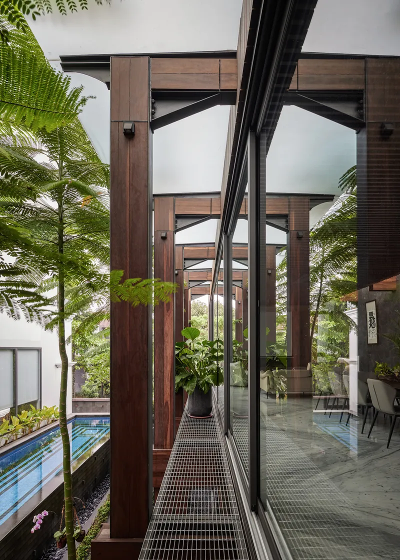 Narrow steel grate walkway framed by timber columns and large ferns in planters