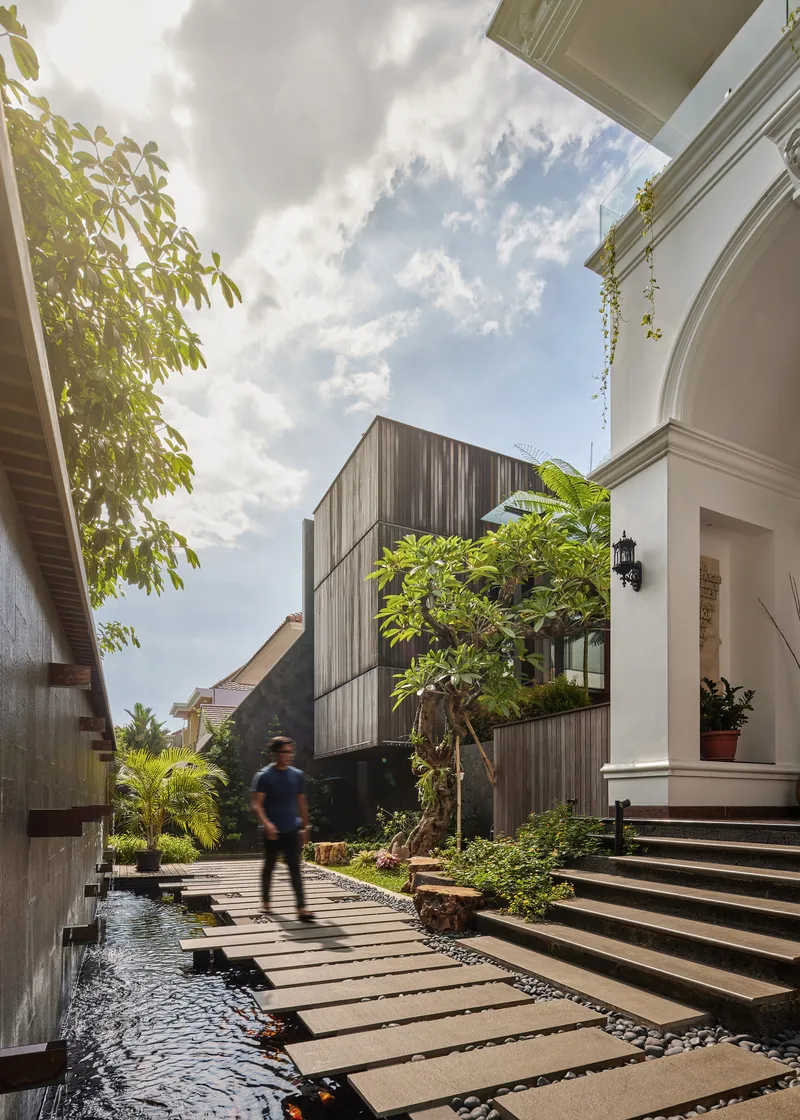 Courtyard pathway with stepping stones over a water feature leading past a person in motion