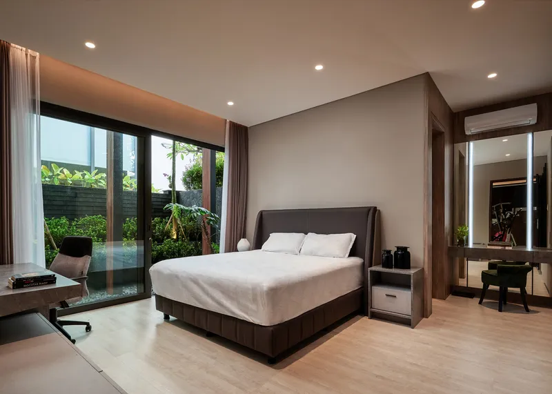 Bedroom with floor-to-ceiling glazing opening to a garden courtyard with tropical plantings