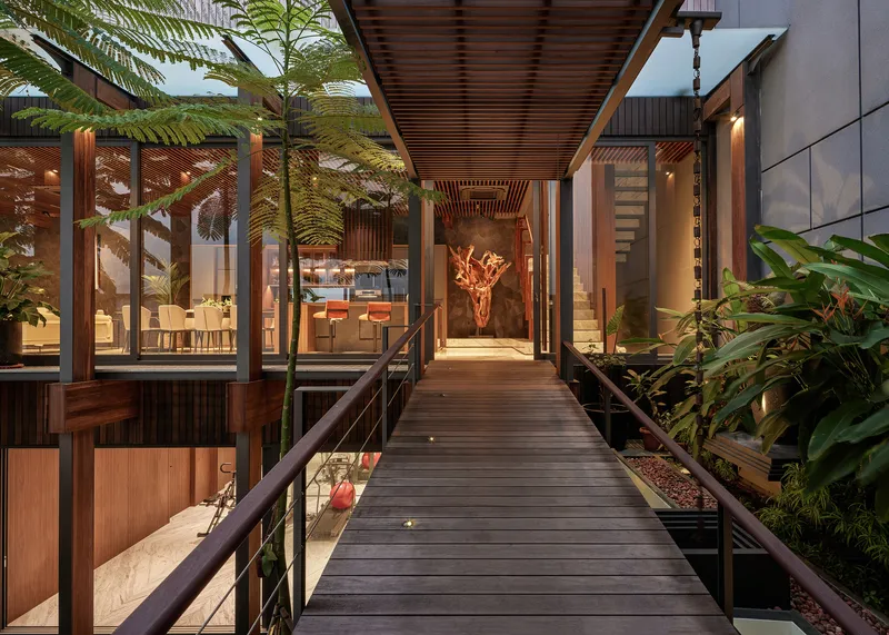 Timber walkway bridging planted garden beds with slatted ceiling overhead at twilight