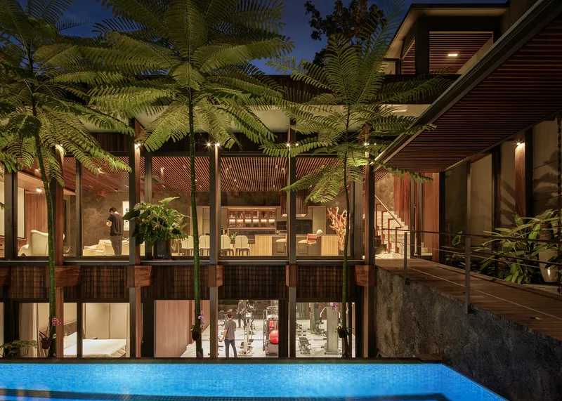 Rear courtyard elevation with full-height glazing, timber columns and illuminated pool at twilight