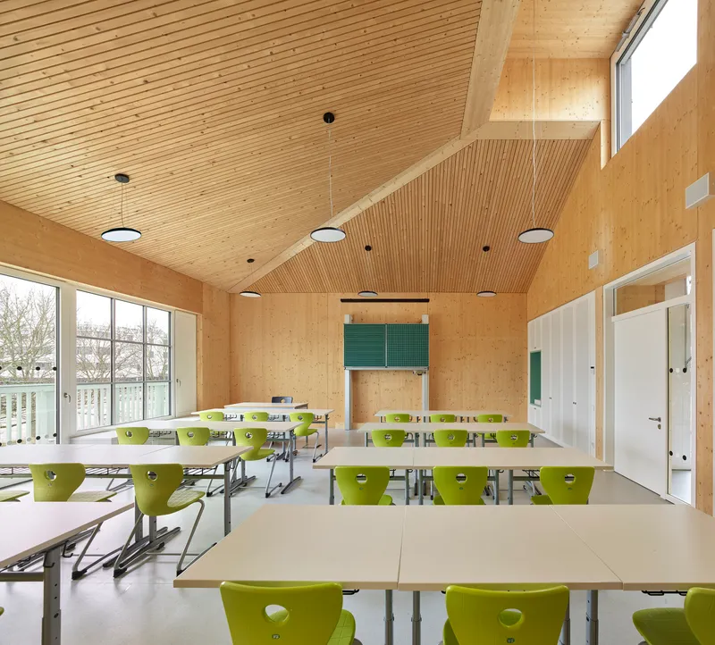 Classroom with lime green chairs at white tables under a slatted timber ceiling