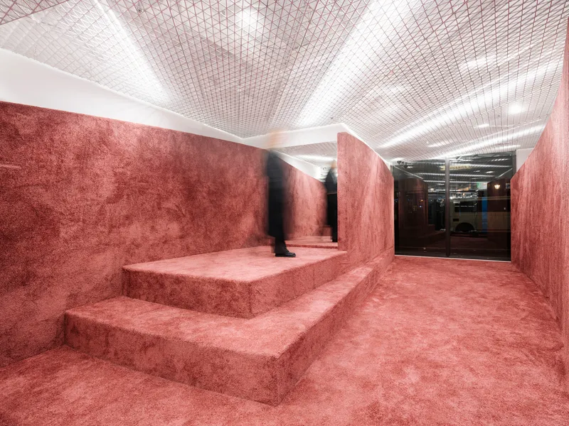 Stepped platform clad entirely in red textured material with a figure standing near the uppermost level