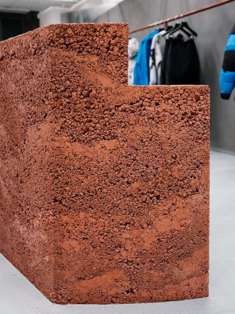Curved reddish aggregate stair detail with clothing rack visible in the background space