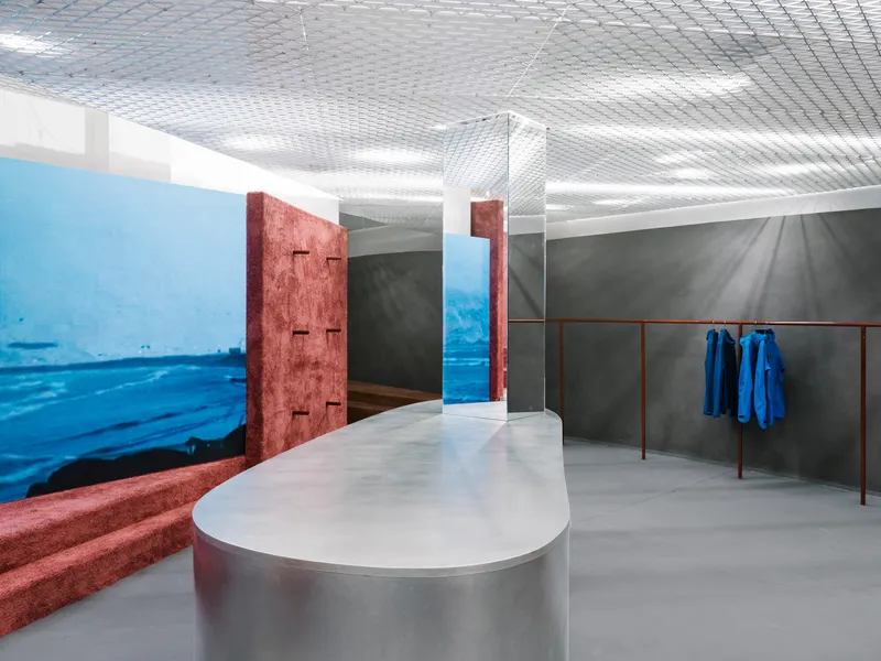 Interior view showing reddish-brown textured columns flanking a doorway with blue garments on a rail