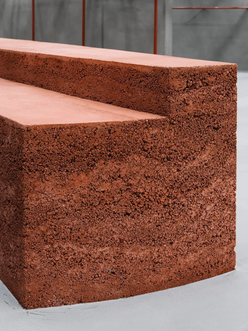 Close-up of reddish porous aggregate steps with smooth tread surfaces against a grey concrete backdrop