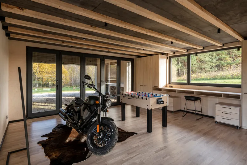 Open interior space with exposed timber ceiling beams, motorcycle on cowhide rug, and foosball table