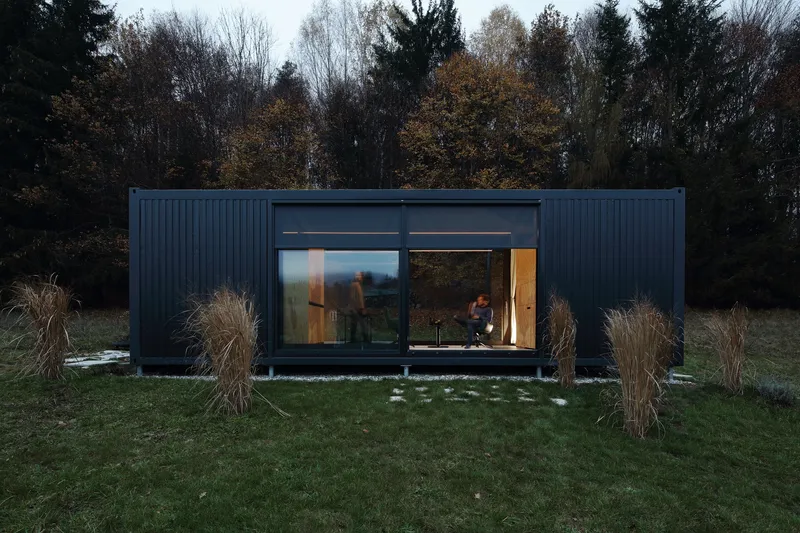 Front elevation showing full-height glazing with occupants inside at dusk