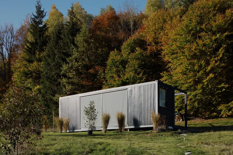 Side elevation showing the corrugated metal cladding and sliding panels against autumn foliage