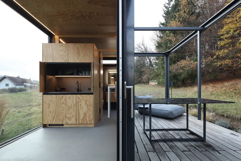 Interior view from the kitchenette looking out through open glass walls to the timber deck