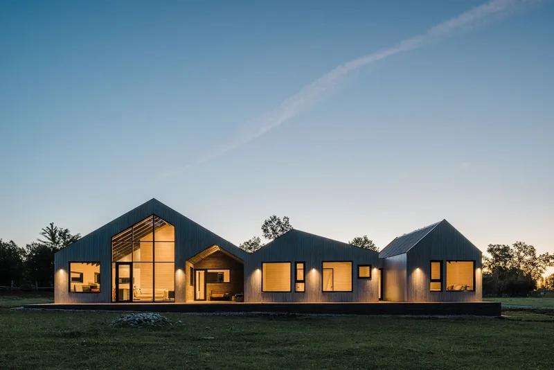 Long view of the clustered gabled forms across an open lawn at twilight
