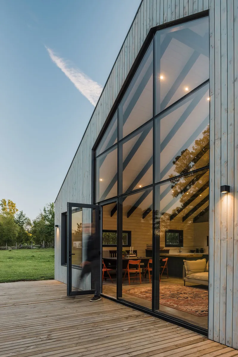 Open glass door revealing exposed timber rafters and interior living space from the timber deck
