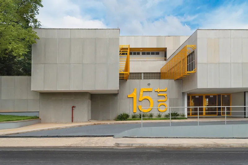 Street view of the concrete panel facade with cantilevered yellow metal box and oversized numerals