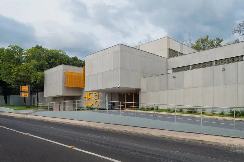 Long view of the stacked concrete volumes with yellow accents under a cloudy sky