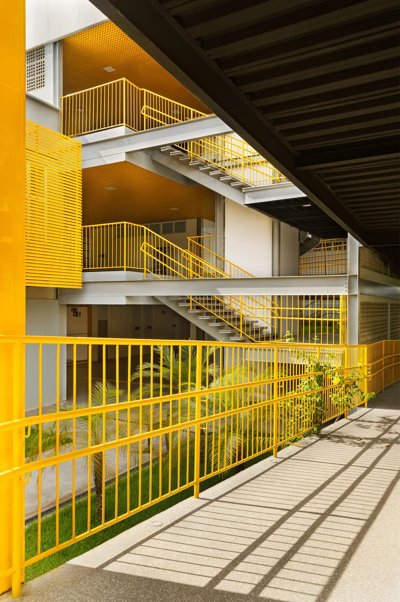 Interior courtyard with yellow metal railings and staircases framing planted beds beneath dark timber ceiling