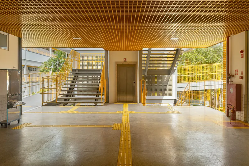 Lobby with yellow tactile pavement strips crossing polished concrete floor beneath slatted timber ceiling