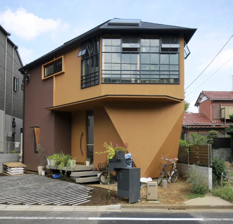 Street view of the cantilevered upper volume with gridded windows and ochre plaster facades