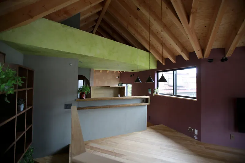 Open plan space with exposed timber rafters connecting kitchen and living area under daylight