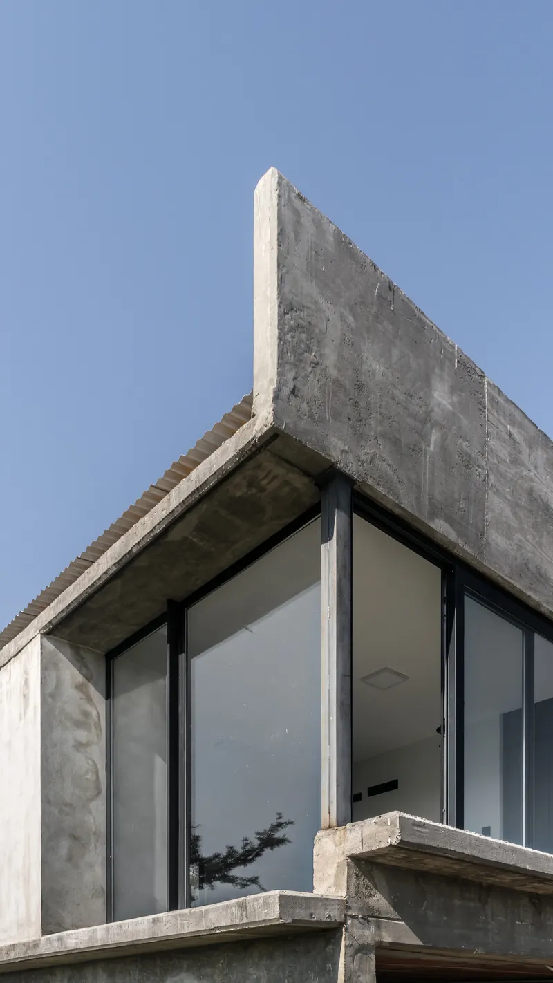 Close-up of the concrete parapet edge and exposed soffit above floor-to-ceiling glass panels