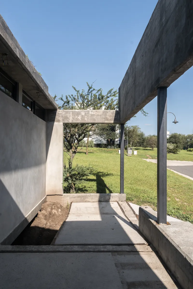 Concrete frame entry threshold with planted tree and view to green lawn beyond