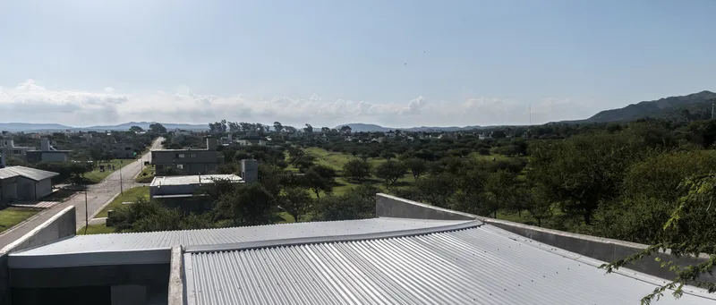 Corrugated metal roof planes extending over the suburban landscape with mountains in distance