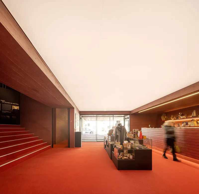 Museum shop interior with red resin floor, wood-clad walls and a visitor in motion