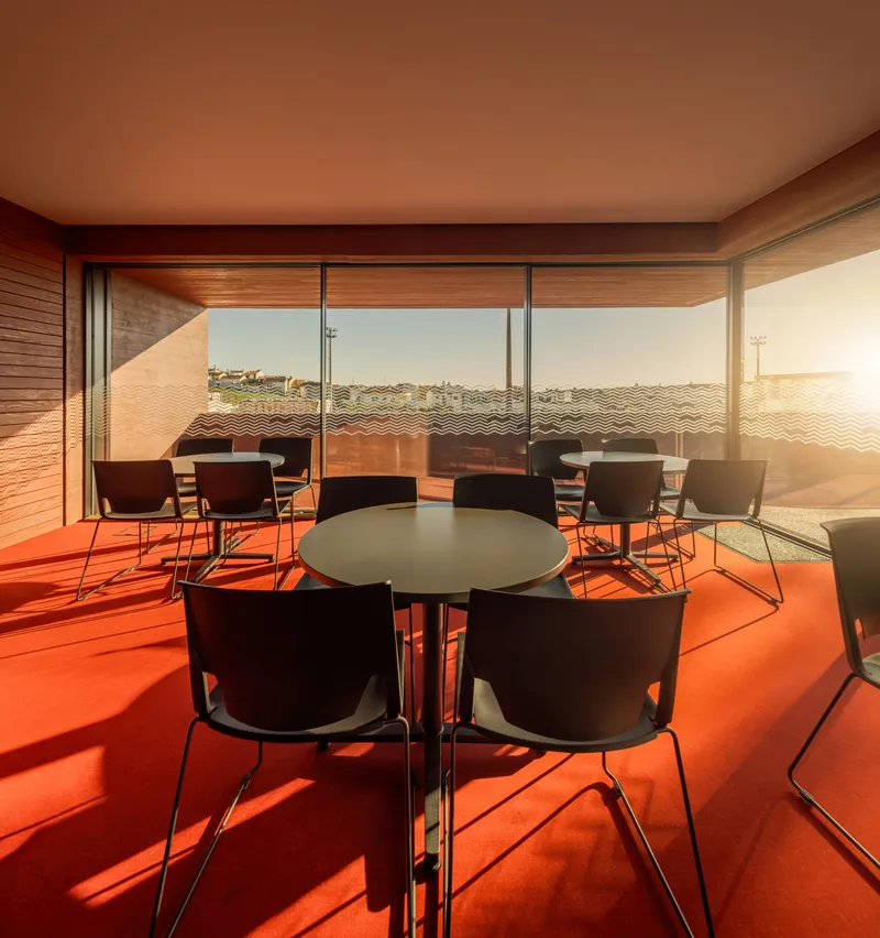 Dining area with orange floor and round tables casting sharp shadows in afternoon sunlight
