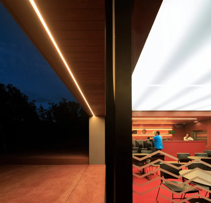 View through the covered terrace with linear lighting along the soffit edge at dusk