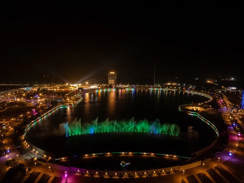 Night view of the circular lake with green illuminated fountain jets along the water surface