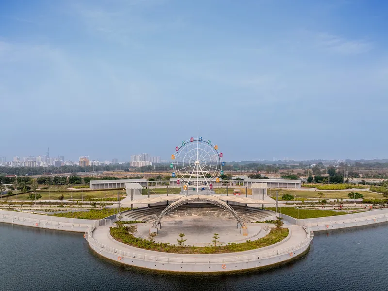 Curved waterfront plaza with a central pavilion and ferris wheel in the distance