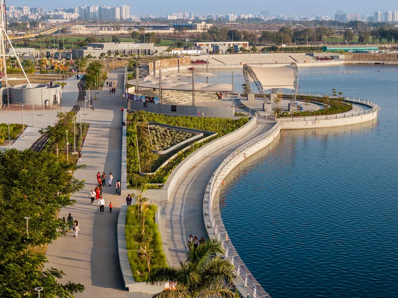 Curving waterfront promenade with planted beds and visitors walking in afternoon light