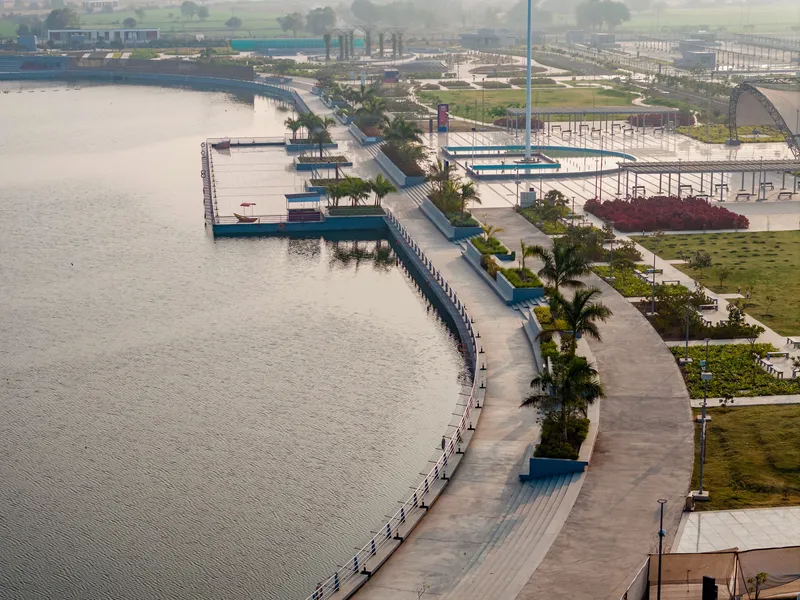 Aerial view of the curving waterfront promenade with planted palm trees and adjacent pier structures